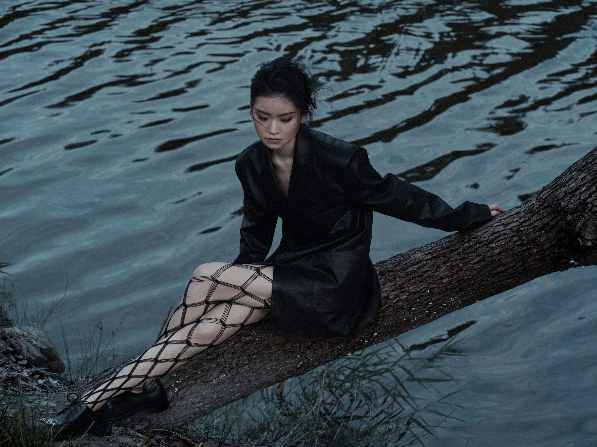 坐在水边倒木上的女性远景
